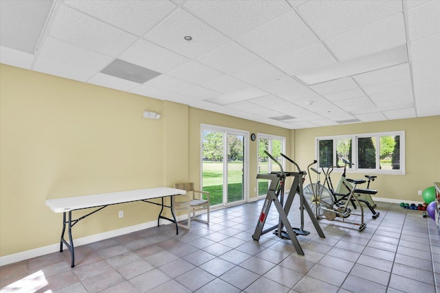 workout area with baseboards, a paneled ceiling, and tile patterned floors