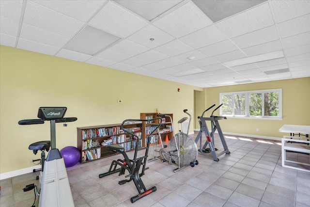 workout room featuring baseboards and a drop ceiling