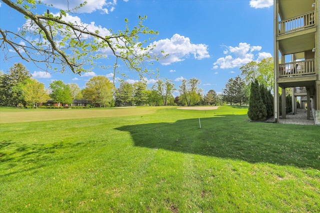view of yard featuring view of golf course and a balcony
