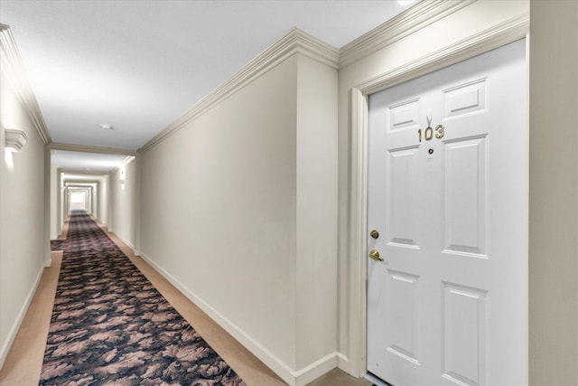 corridor featuring baseboards, ornamental molding, and light carpet
