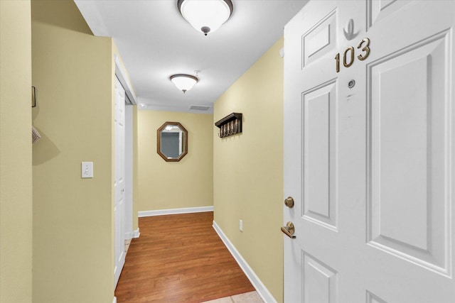 hallway with visible vents, baseboards, and light wood finished floors
