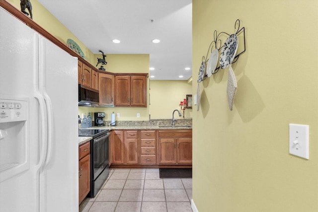 kitchen featuring a sink, white refrigerator with ice dispenser, black electric range oven, stainless steel microwave, and light tile patterned floors