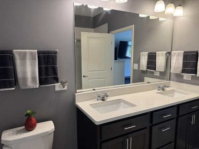 bathroom with a sink, toilet, and double vanity