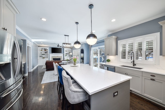 kitchen featuring a fireplace, a sink, appliances with stainless steel finishes, and crown molding