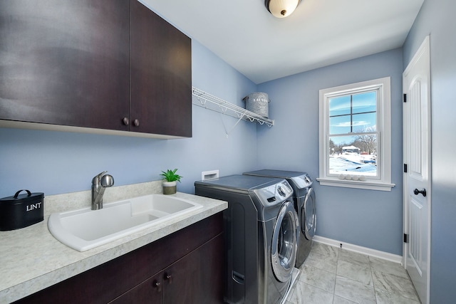 clothes washing area with baseboards, a sink, independent washer and dryer, and cabinet space
