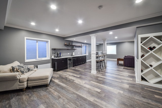 bar featuring wine cooler, ornamental molding, dark wood-type flooring, decorative columns, and indoor wet bar