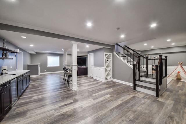 basement featuring stairway, a sink, baseboards, dark wood-type flooring, and wine cooler