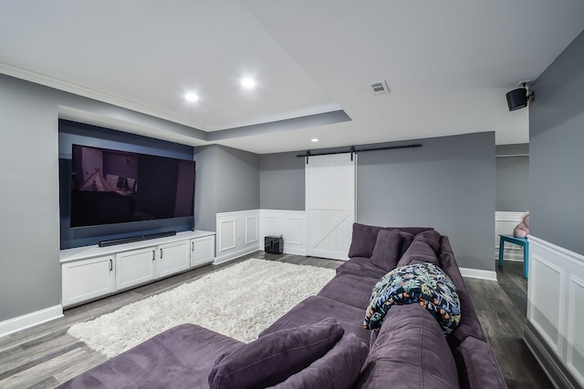 living area featuring dark wood finished floors, a barn door, a wainscoted wall, and visible vents