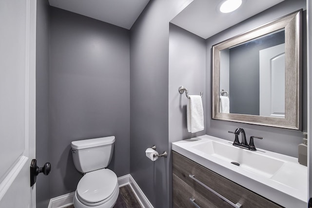 bathroom featuring toilet, vanity, wood finished floors, and baseboards