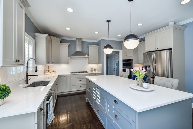 kitchen featuring a center island, a sink, wall chimney exhaust hood, appliances with stainless steel finishes, and recessed lighting