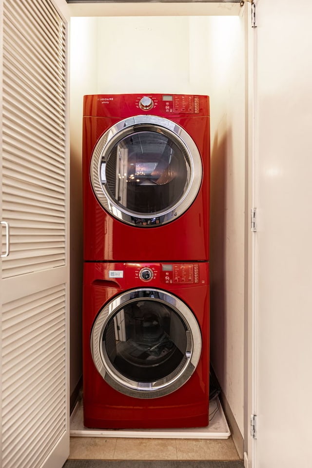 laundry area featuring tile patterned flooring, stacked washer / dryer, and laundry area