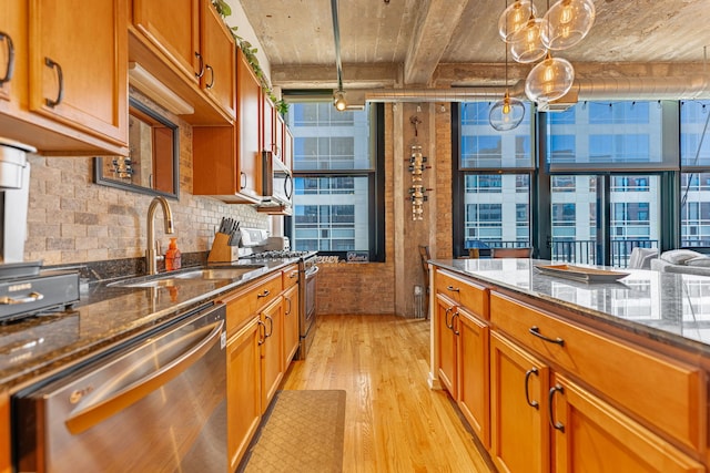 kitchen featuring brown cabinets, stainless steel appliances, light wood finished floors, and a sink