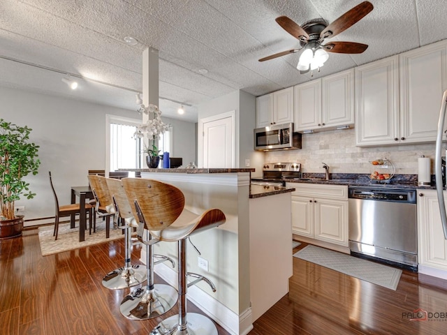kitchen featuring dark wood-style flooring, a kitchen breakfast bar, stainless steel appliances, and a sink