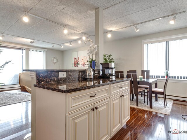 kitchen with dark wood finished floors, track lighting, a center island, and dark stone counters