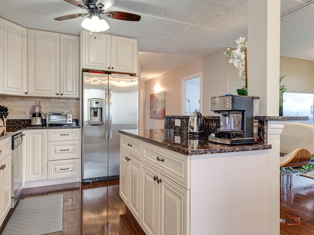 kitchen with ceiling fan, appliances with stainless steel finishes, dark stone countertops, and dark wood-type flooring