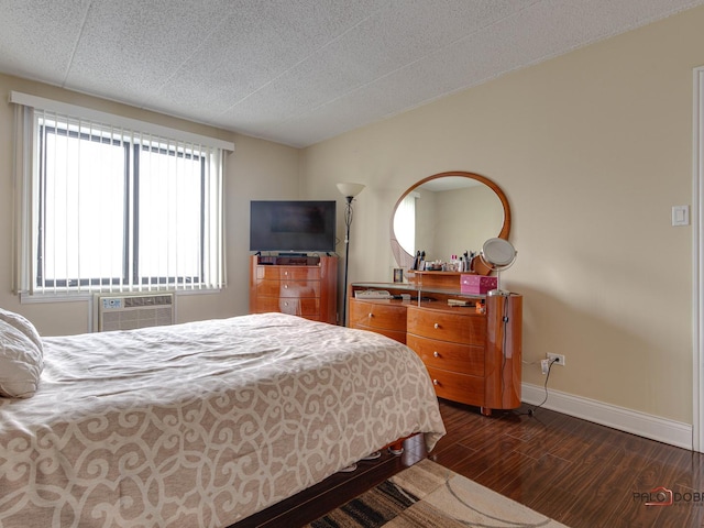 bedroom featuring a wall mounted air conditioner, baseboards, a textured ceiling, and dark wood-style floors