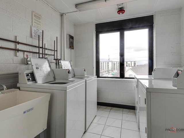 community laundry room featuring washing machine and dryer, concrete block wall, and a sink