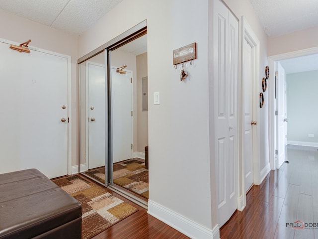 hallway with baseboards, wood finished floors, and a textured ceiling