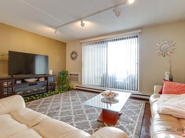 living room featuring track lighting, an AC wall unit, wood finished floors, and a baseboard radiator