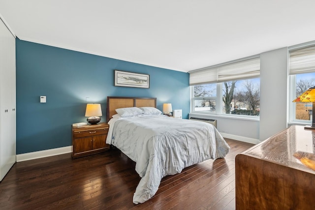 bedroom with ornamental molding, baseboards, and dark wood-style flooring