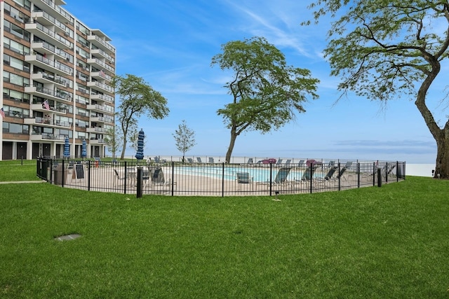 community pool featuring fence and a lawn