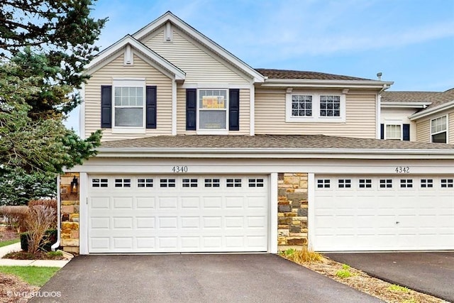 view of front of property with stone siding, a shingled roof, driveway, and a garage