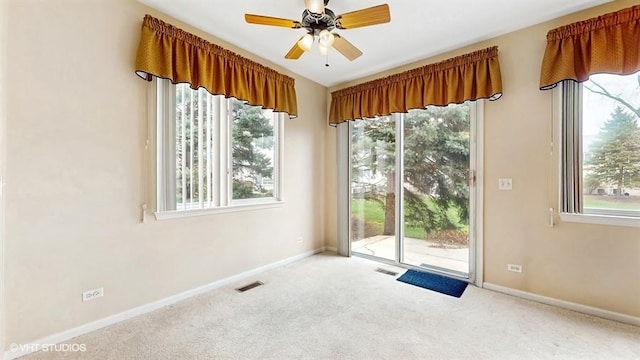 carpeted spare room featuring visible vents, baseboards, and ceiling fan