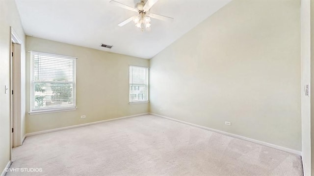 empty room with lofted ceiling, visible vents, a ceiling fan, baseboards, and carpet flooring