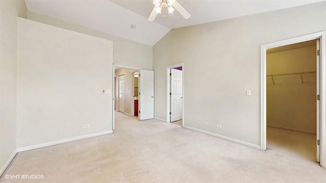 unfurnished bedroom featuring a walk in closet, light carpet, lofted ceiling, and baseboards