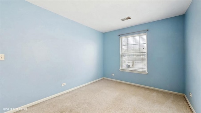 spare room featuring light carpet, baseboards, and visible vents