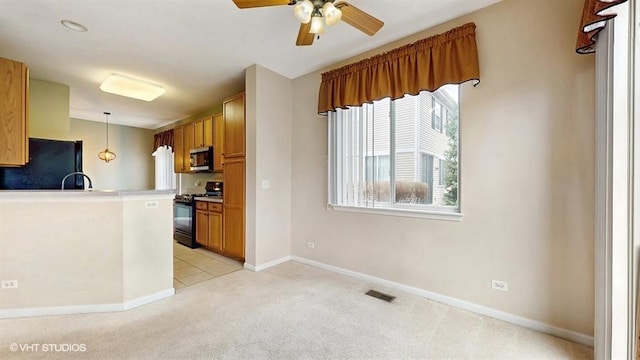 kitchen featuring brown cabinets, black range with gas stovetop, stainless steel microwave, fridge, and ceiling fan