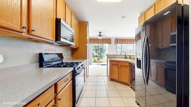 kitchen featuring a ceiling fan, a sink, black appliances, light tile patterned floors, and light countertops