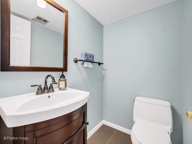 half bathroom with toilet, baseboards, visible vents, and vanity