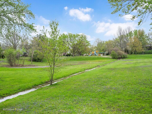 wooden terrace featuring a lawn, outdoor dining area, and a playground