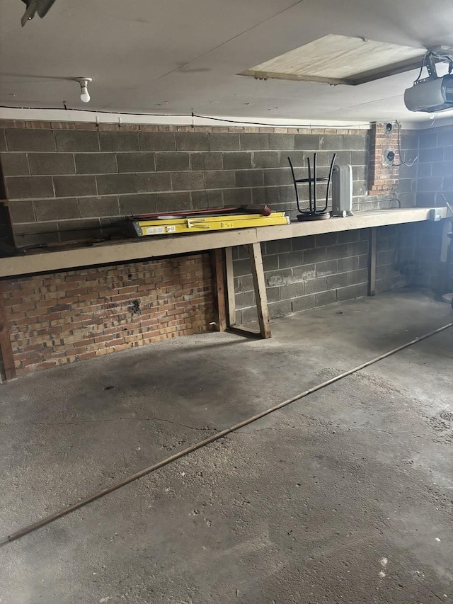 garage featuring concrete block wall, a workshop area, and a garage door opener