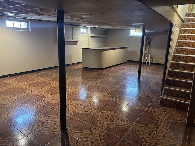 basement featuring a healthy amount of sunlight, stairs, and dark floors