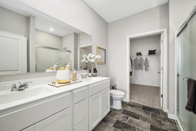 bathroom featuring double vanity, a spacious closet, a stall shower, and a sink