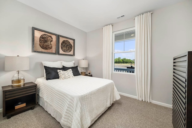 bedroom with visible vents, light carpet, and baseboards