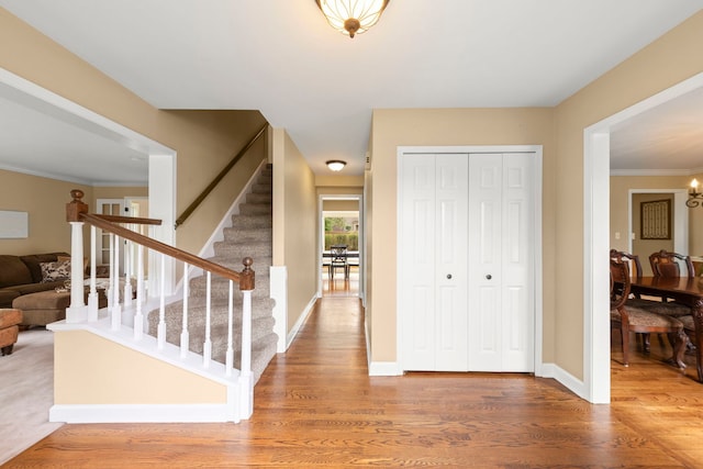 entrance foyer featuring stairway, baseboards, ornamental molding, and wood finished floors