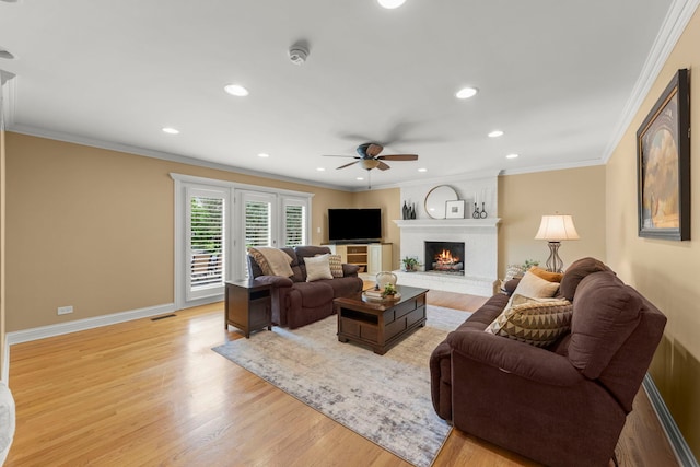 living area with a fireplace, light wood-style flooring, a ceiling fan, baseboards, and visible vents
