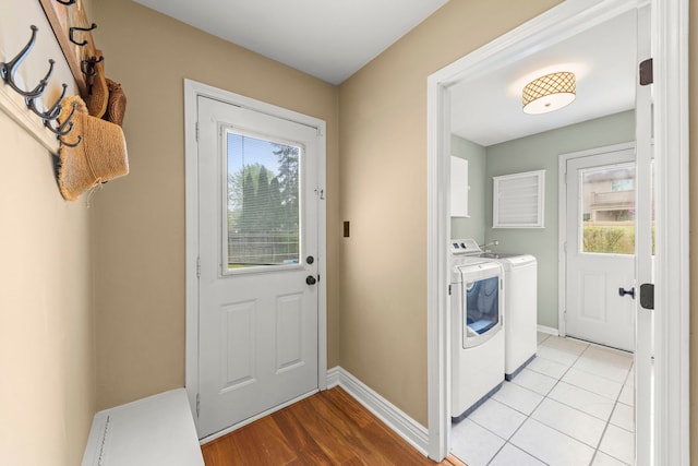 laundry room with baseboards, light wood-style flooring, cabinet space, and washing machine and clothes dryer