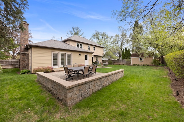 rear view of property with an outdoor structure, a fenced backyard, a chimney, a patio area, and a yard