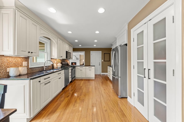 kitchen with recessed lighting, a sink, light wood-style flooring, appliances with stainless steel finishes, and backsplash