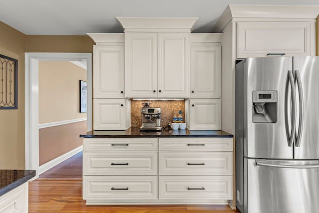 kitchen with stainless steel fridge with ice dispenser, baseboards, white cabinets, light wood finished floors, and dark stone countertops