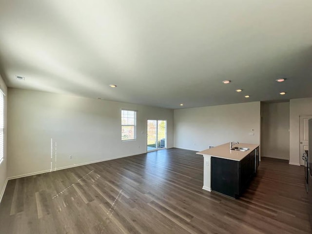 interior space with dark wood-style flooring, open floor plan, a sink, and light countertops