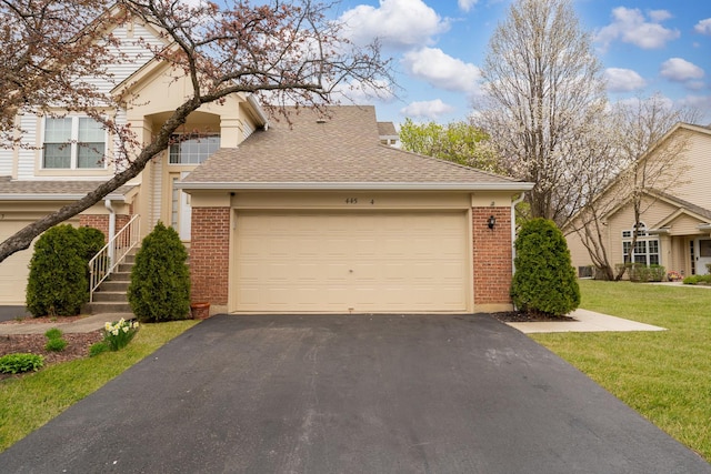 townhome / multi-family property with brick siding, an attached garage, a shingled roof, and aphalt driveway