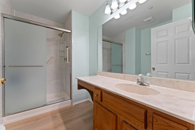 bathroom with vanity, a stall shower, baseboards, and wood finished floors