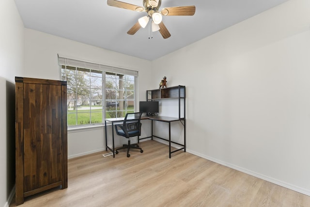 office featuring baseboards, a ceiling fan, and light wood-style flooring