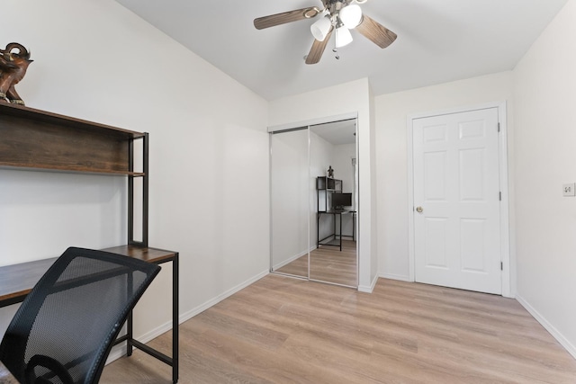 office space featuring baseboards, a ceiling fan, and light wood finished floors