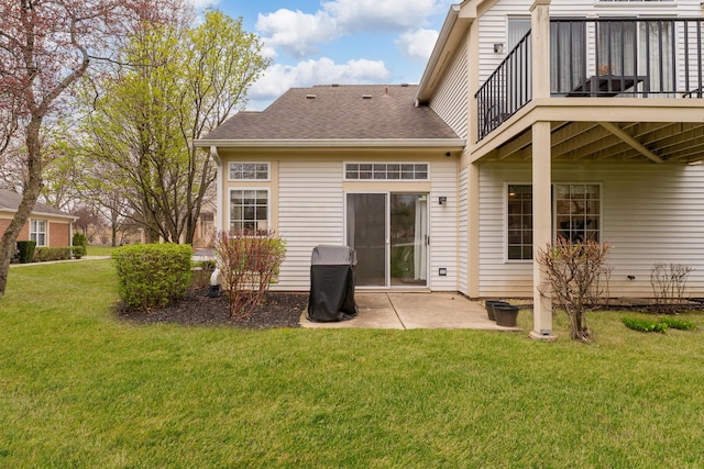 rear view of house with a yard, a patio, a shingled roof, and a balcony